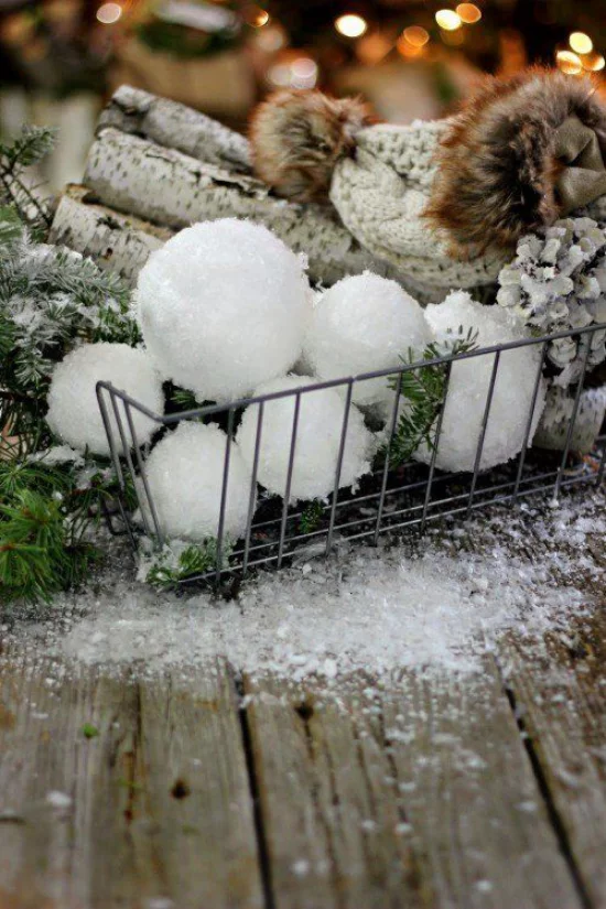 Schneebälle Winterdekoration mit Brennholz Tannengrün Mütze aus Wolle Zapfen im Gitter