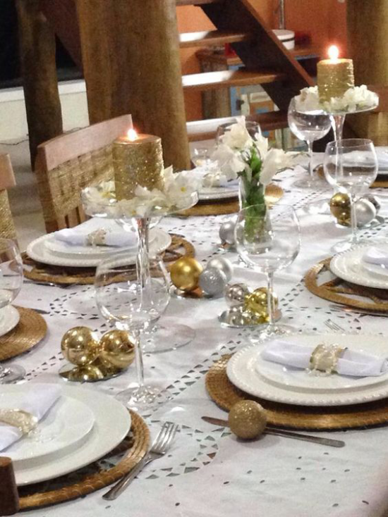 Silvester feiern zu Hause Gold-und Silberkugeln Kerzen weiße Blüten den festlich gedeckten Tisch zum Strahlen bringen
