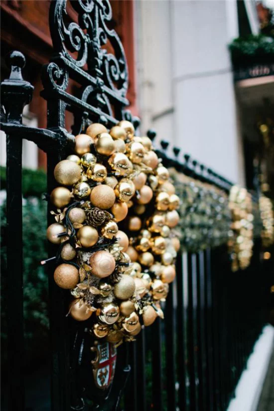 Weihnachtsdeko in Gold und Schwarz Kranz aus goldenen Weihnachtskugeln auf schwarzem Hintergrund Zaun