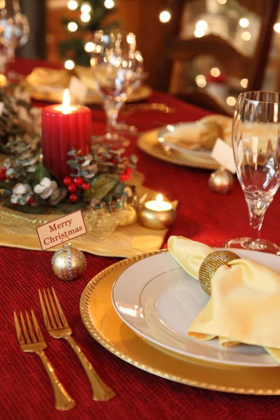 Weihnachtsdeko in Rot und Gold festlich gedeckter Tisch rote Tischdecke edles Porzellan vergoldetes Besteck rote Kerze