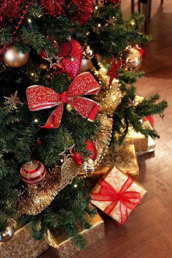 Weihnachtsdeko in Rot und Gold große rote Schleife Kugeln Girlanden zahlreiche Geschenke unter dem Christbaum