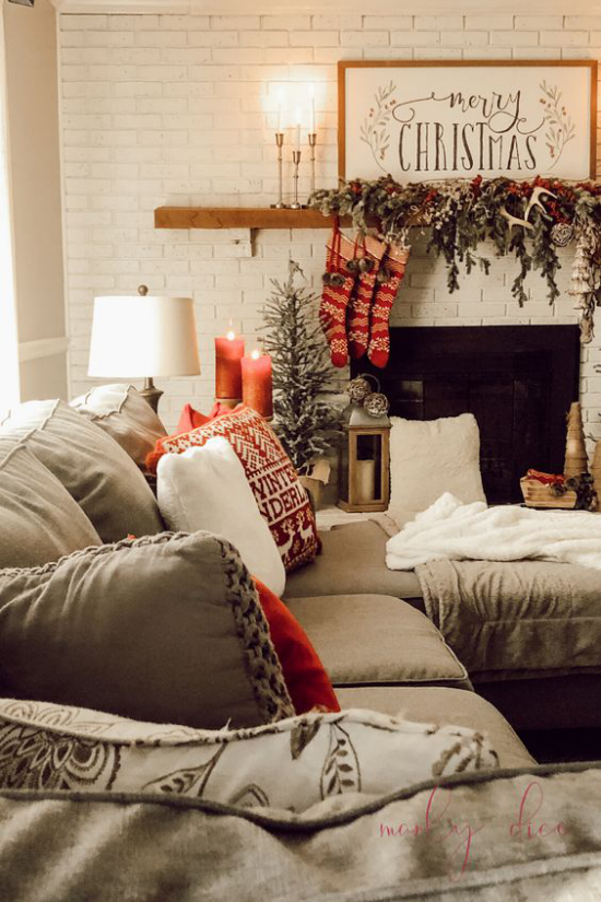 traumhafte Weihnachtsdeko im Wohnzimmer bequeme Couch Kamin Tannengrün rote Stiefel Kerzen