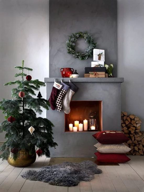 traumhafte Weihnachtsdeko im Wohnzimmer kleiner Christbaum Kamin Kerzen grauer Hintergrund Industrial Style