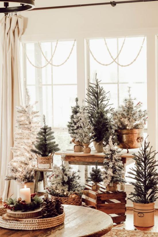 traumhafte Weihnachtsdeko im Wohnzimmer viele kleine Tannenbäume vor dem Fenster arrangiert