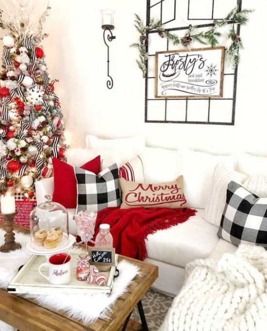 traumhafte Weihnachtsdeko im Wohnzimmer weiße Couch rote Akzente kuschelige Decke Kissen Tannenbaum links