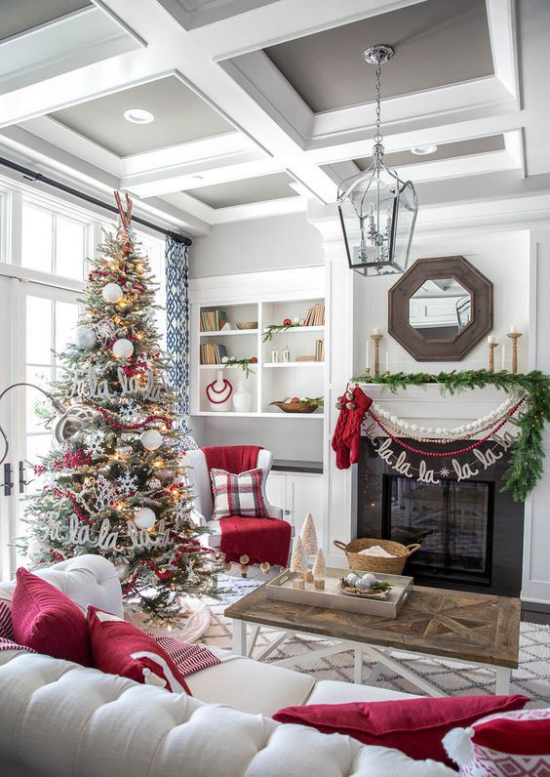 traumhafte Weihnachtsdeko im Wohnzimmer weiße Couch rote Kissen Tannenbaum grüne Girlande am Kamin