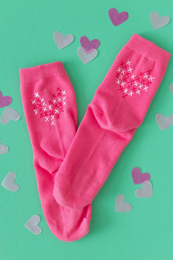 DIY Geschenke zum Valentinstag ein Paar rosa Socken fein bestrickte Herzen darauf Zeichen für Liebesgefühle
