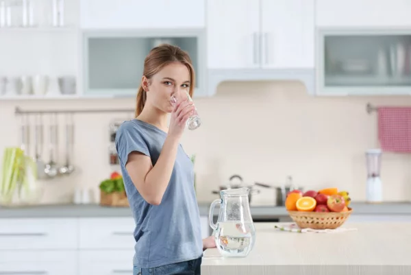 Getränke gegen Corona  viel Wasser trinken junges Mädchen in der Küche