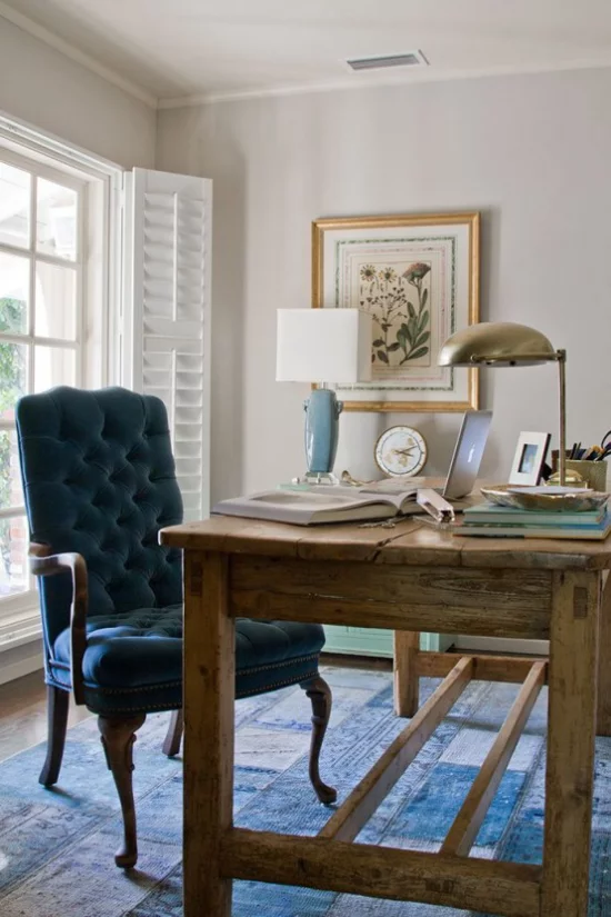 Home Office im Landhausstil Massivholztisch marineblauer Sessel blauer Teppich Lampen Wandbild stilvolle Raumgestaltung