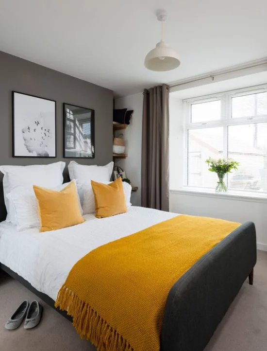 Trendfarben 2021 im Interieur gemütliches Schlafzimmer viel Wärme ausstrahlen gelbe Decke Kissen graue Akzentwand ideen