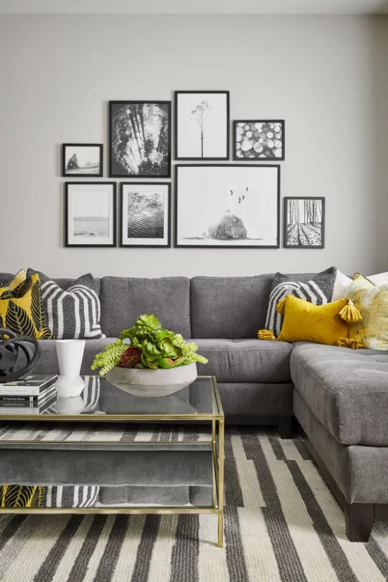 Trendfarben 2021 im Interieur gemütliches Wohnzimmer Wandbilder graues Sofa kleine gelbe Akzente erfrischen das Ambiente