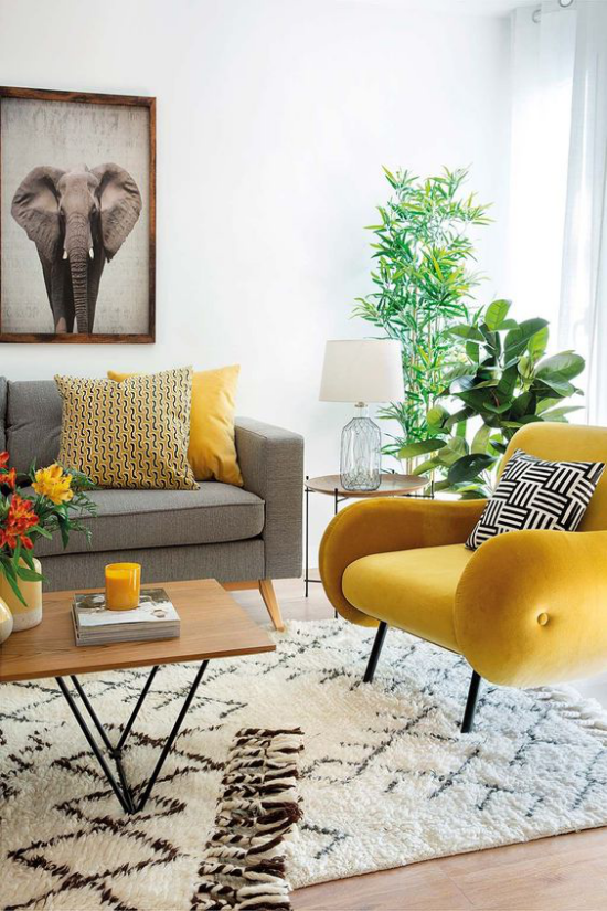 Trendfarben 2021im Interieur Wohnzimmer graues Sofa gelber Sessel Teppich immergrüne Zimmerpflanzen viel Sonnenlicht