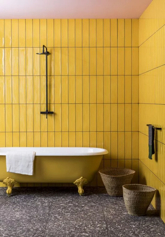 Badezimmer Trends 2021 Retro Design gelbe Wandpaneele gelbe Badewanne mit Löwenfüßen dunkler Terrazzoboden