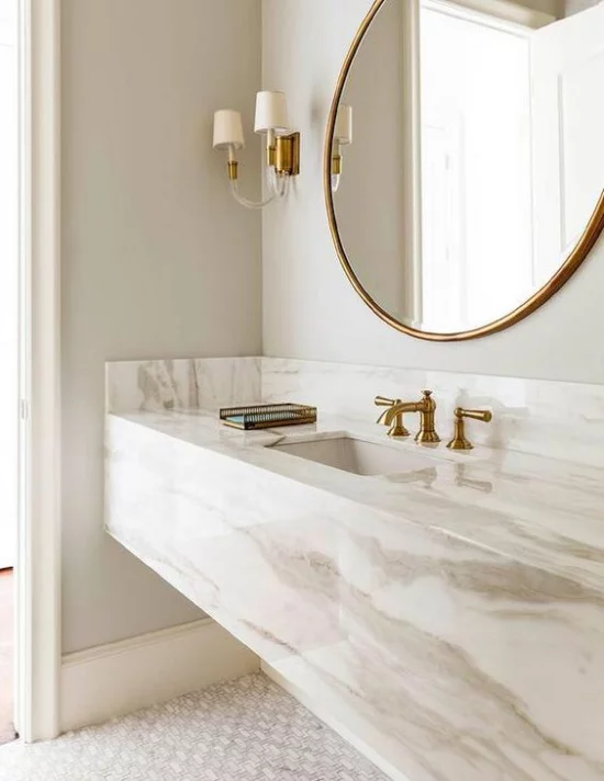 Badezimmer Trends 2021 elegantes Baddesign weißer Marmor Waschtisch großer runder Spiegel Wandlampen