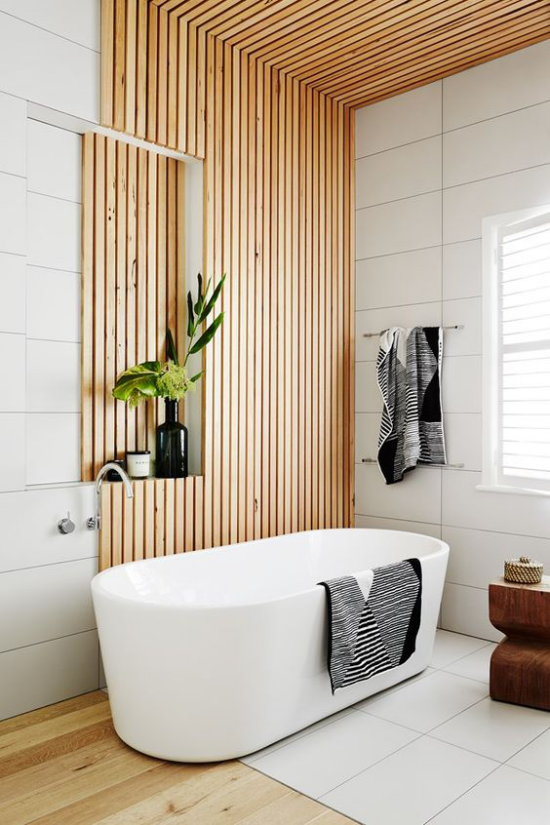 Badezimmer Trends 2021 schickes Baddesign Holzpaneele Holzboden weiße Badewanne weiße Fliesen Tücher