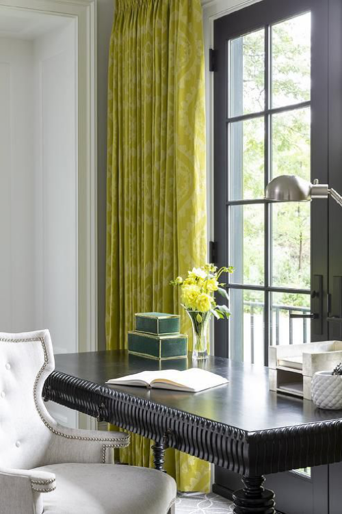 gelbe Akzente im Home Office Büro Inspiration klassischer schwarzer Schreibtisch weißer Sessel gelbgrüne Gardinen Vase mit gelben Blumen