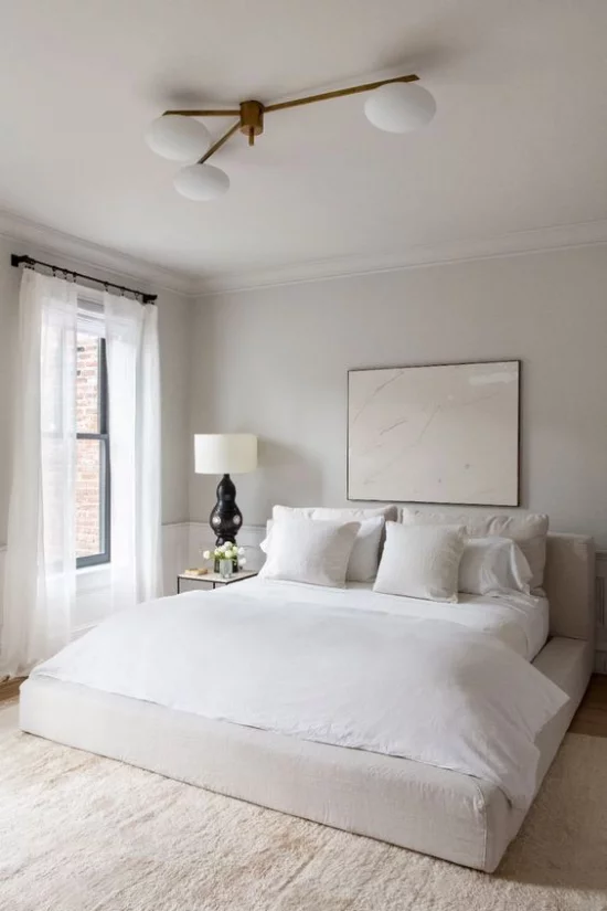 kleines Schlafzimmer optisch erweitern helles Ambiente neutrale Farben Wandbild dezentes Licht Fenster weiße Gardinen