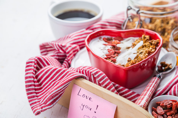 romantisches Frühstück zu zweit Kaffee Müsli mit Joghurt Erdbeeren in Herzform