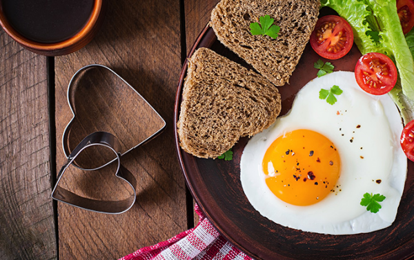 romantisches Frühstück zu zweit gesunde Ernährung Vollkornbrot Spiegelei in Herzform Tomate Salatblatt