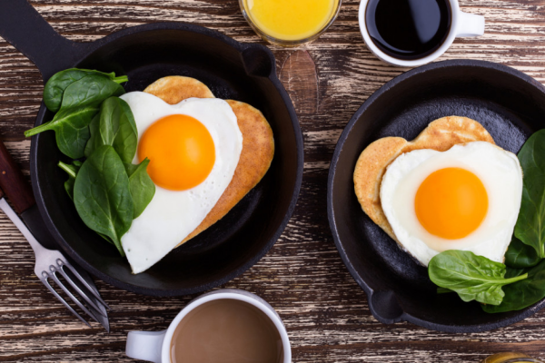 romantisches Frühstück zu zweit pfannkuchen gebratene Eier in herzform Spinat