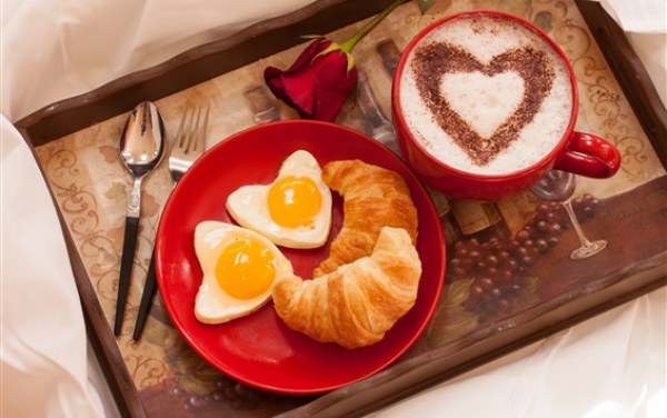 romantisches Frühstück zu zweit  rotes Geschirr Cappuccino Herzform Croissants gebratene Eier in Herzform auf Tablett rote Rose
