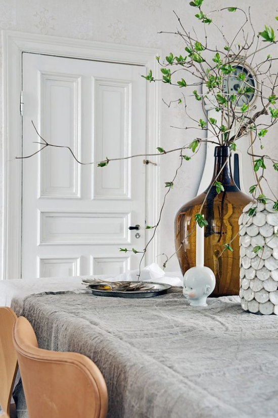 skandinavische Frühlingsdeko auf dem Tisch hohe Vase Zweige grüne Blätter einfach und schön