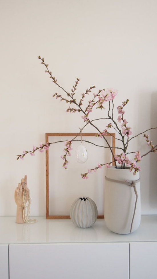 skandinavische Frühlingsdeko auf der Kommode elegantes Arrangement rosa Kirschblüten