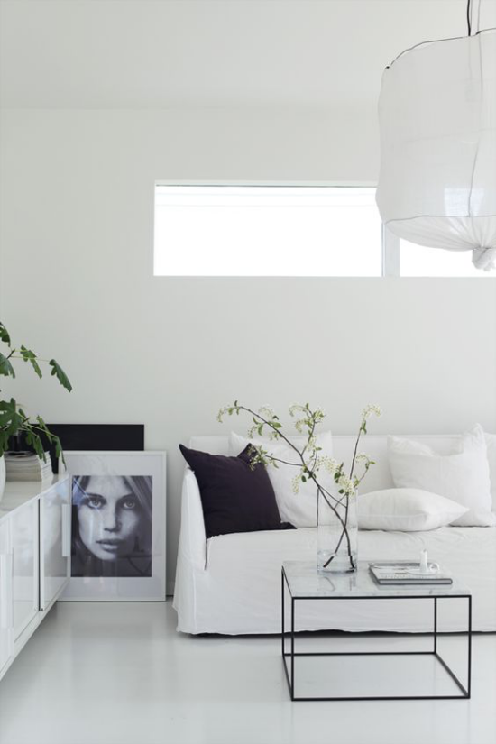 skandinavische Frühlingsdeko sehr elegantes Interieur weiße Möbel großes Bild Glastisch Glasvase Zweige