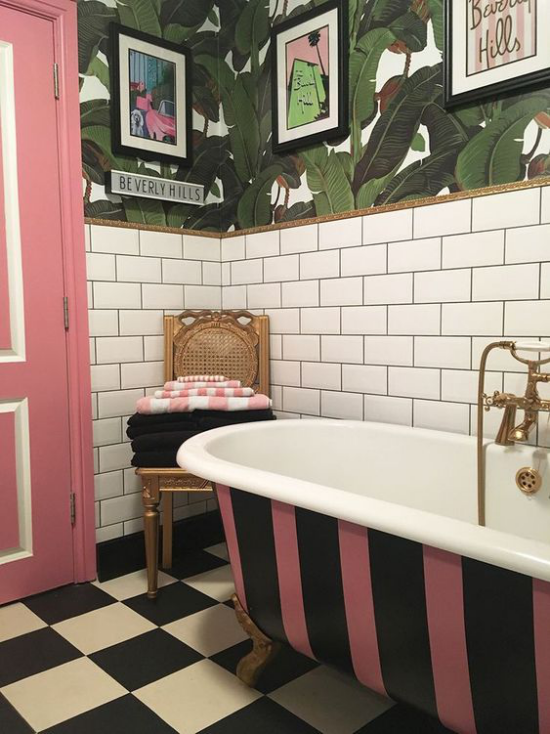 Tropische Deko im Bad im Retro Stil freistehende Badewanne rosa schwarz gestreift rosa Tür Wandtapeten Tücher auf dem Stuhl