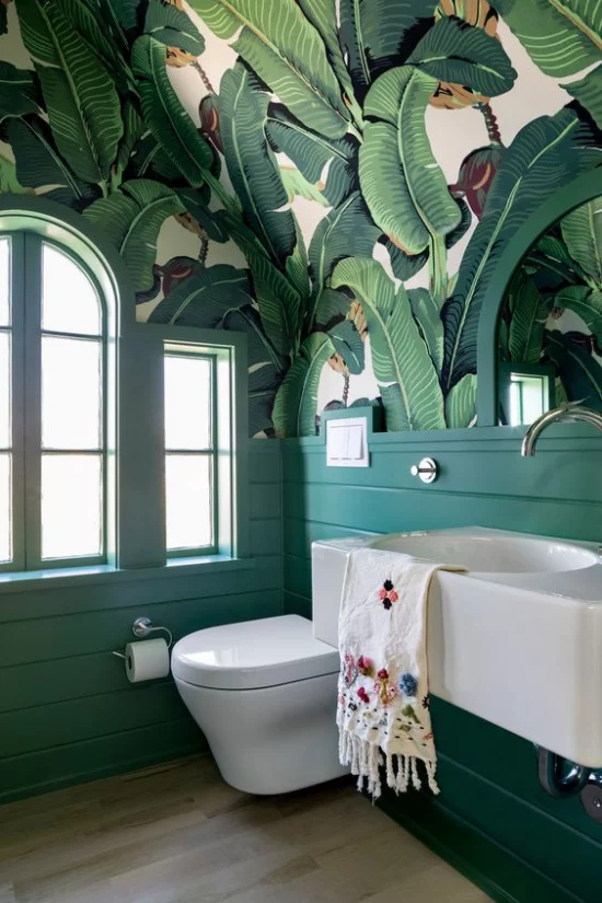 Tropische Deko im Bad schöne Tapete große Blätter weiße Badezimmermöbel WC Bodenfliesen links Fenster