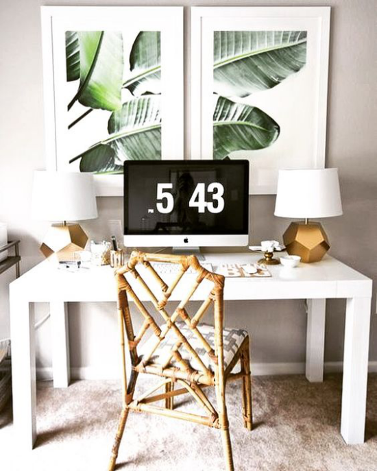 Tropische Deko im Home Office Naturmaterialien Holztisch Rattan-Sessel Uhr zwei Wandbilder tropische Blätter