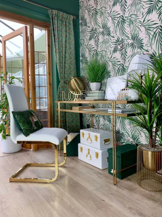 Tropische Deko im Home Office großer heller Raum grüne Farbe dominiert Schreibtisch Sessel Akzentwand Tapete große tropische Blätter grüne Topfpflanzen