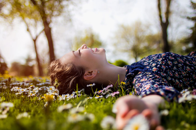 Weltfrauentag am 8.März junge Frau im Park liegt im Gras in der Sonne glücklich sein