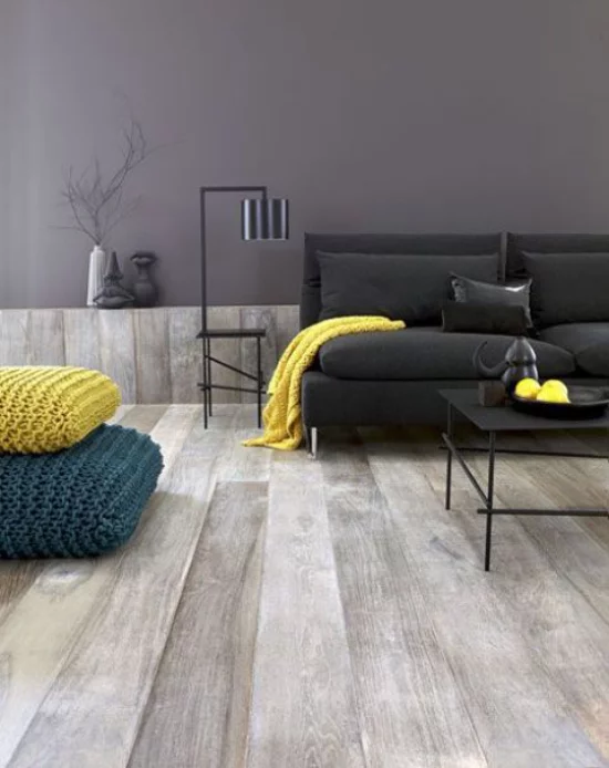 grauer Boden gelbe Akzente Wohnzimmer Blickfang schwarzes Sofa