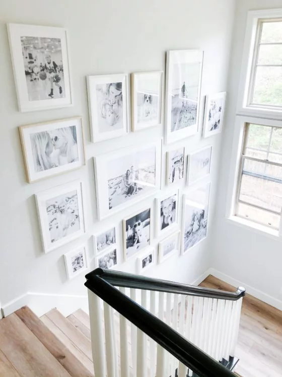 Fotowand im Treppenhaus viele Bilder in weißen Rahmen viel Tageslicht schöne Gestaltung