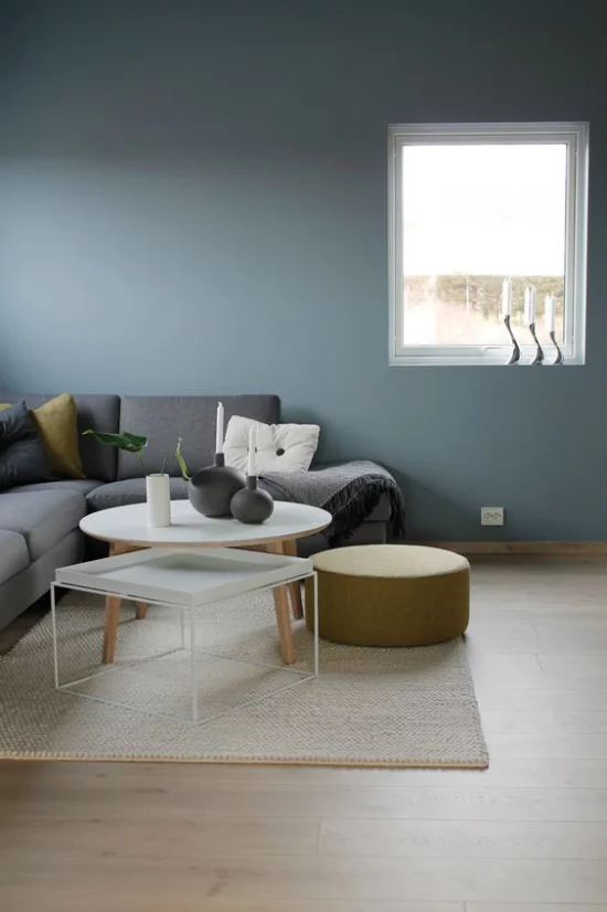 Mehr Farbe ins Interieur bringen heller Teppich graues Sofa blaue Wandfarbe einheitliches Gestaltungskonzept Wohnzimmer