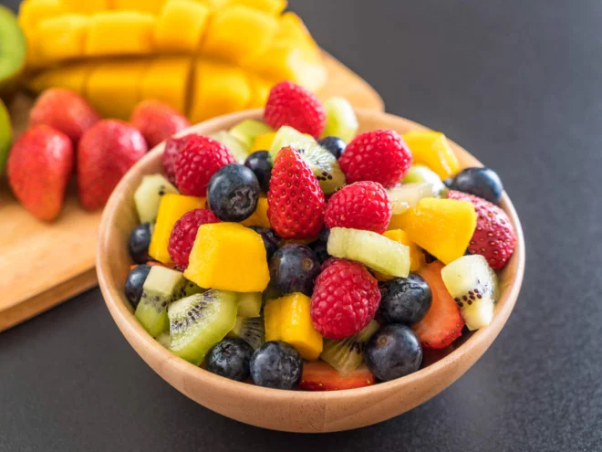 Obst essen gesund abnehmen Schale frische Früchte Erdbeeren Blaubeeren Ananas Kiwi in Stücke geschnitten