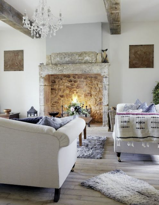 Provence-Stil gemütliches stilvoll gestaltetes Wohnzimmer Sitzgarnitur in hellem Grau Akzente in Lavendel Teppich Kissen Steinkamin