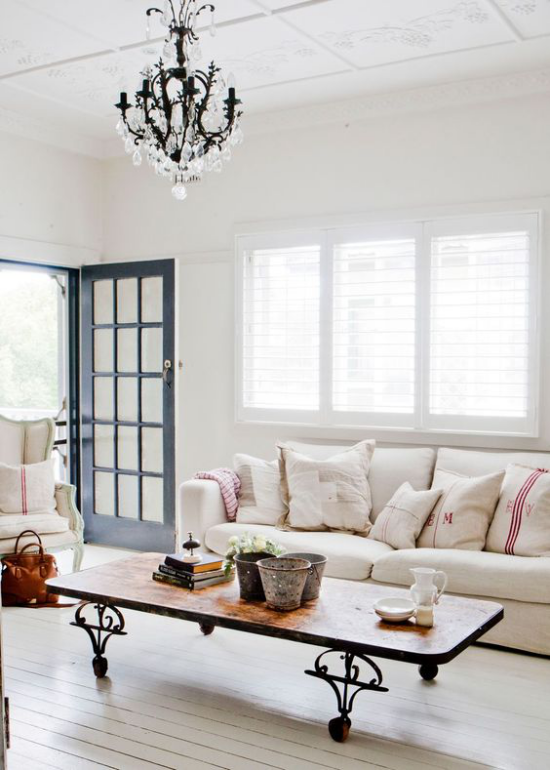 Provence-Stil helles lichtdurchflutetes Wohnzimmer einfache Möbel offene Tür kahler Boden