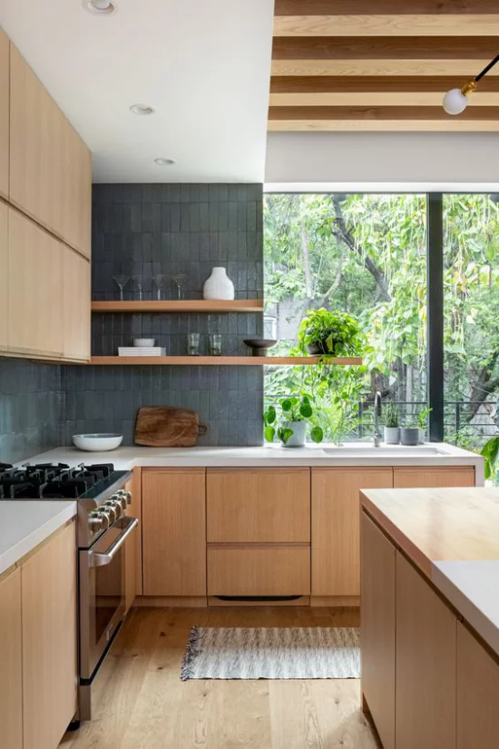 Helles Holz im Interieur moderne Küche Ober-und Unterschränke Herd Spüle Blick ins Freie viel Grün