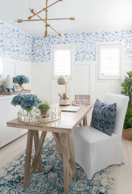 Home Office maritim einrichten interessante Raumgestaltung in Blau starke visuelle Wirkung leicht gemusterte Tapeten Teppich Deko Kissen blaue Hortensien in Vase