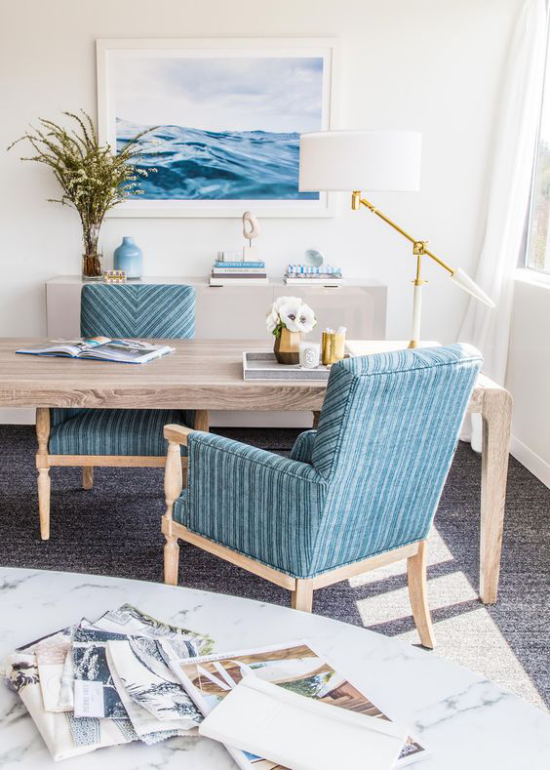Home Office maritim einrichten sanfte Blautöne Wandbild Sessel viel natürliches Holz Gräser in Vase weiße Tischlampe