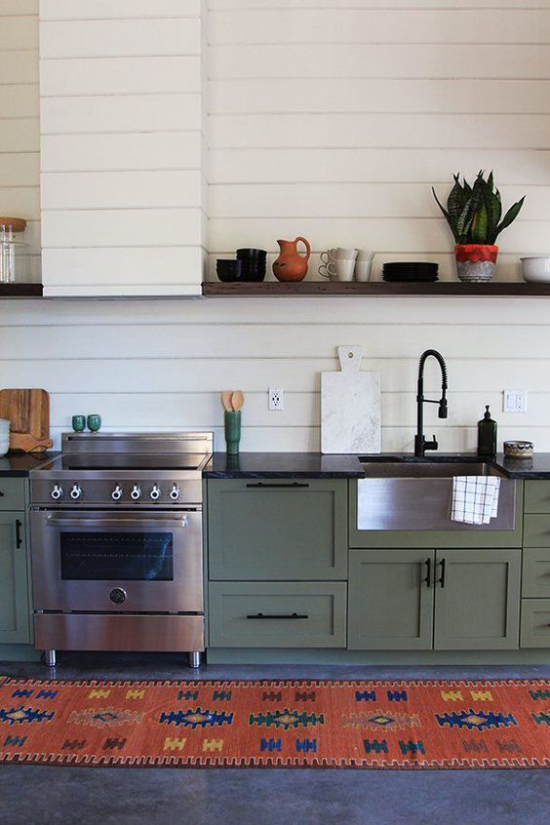 Küchenzeile im Retro Stil grüne Küchenschränke moderner Herd rustikaler Läufer gemustert