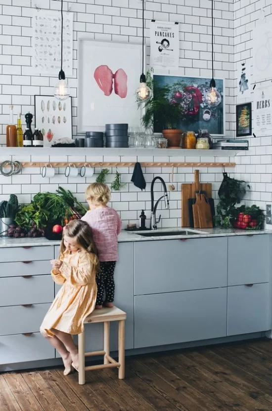 Küchenzeile im Retro Stil hellblaue Schränke zwei kleine Kinder Hocker Gemüse auf der Arbeitsplatte