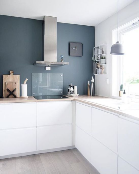 L-Küche weiße Unterschränke dunkelblaue Wand in Farbkontrast Dunstabzugshaube