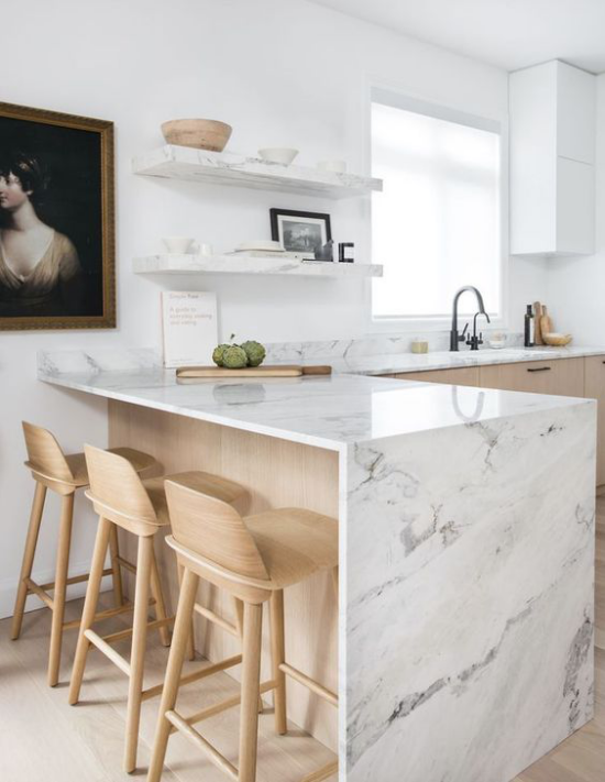 L-Küche weißer Marmor Kücheninsel Arbeitsplatten helles Holz Regale klassisches Gemälde an der Wand