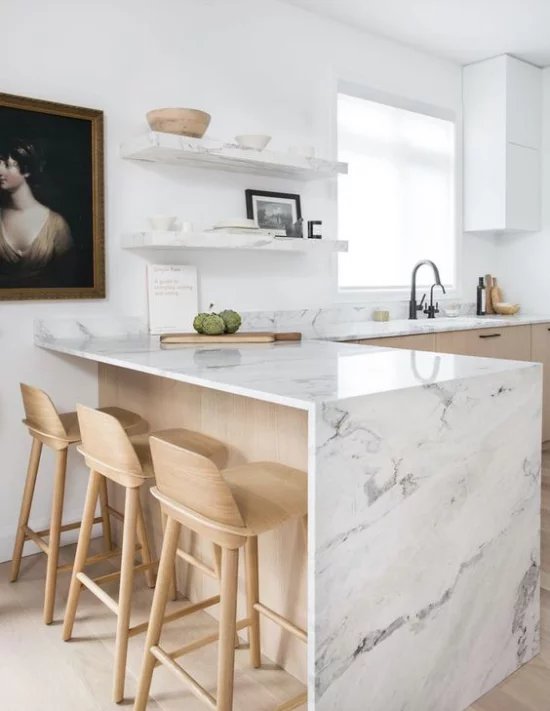 L-Küche weißer Marmor Kücheninsel Arbeitsplatten helles Holz Regale klassisches Gemälde an der Wand