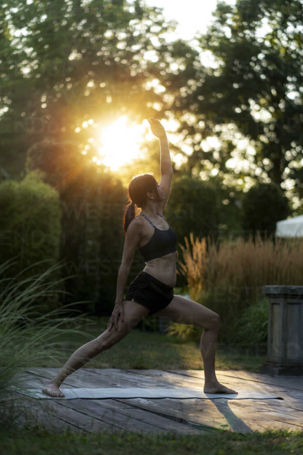 Yoga Garten anlegen und gestalten im Sonnenuntergang junge Frau Yoga Matte Übungen im Freien
