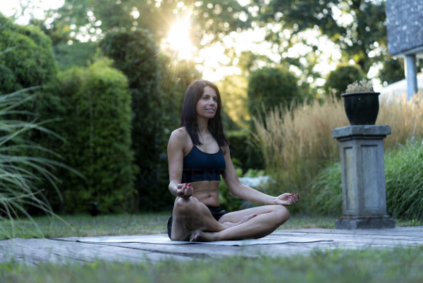 Yoga Garten anlegen und gestalten junge Frau bei Yoga Übungen und Meditation im Garten