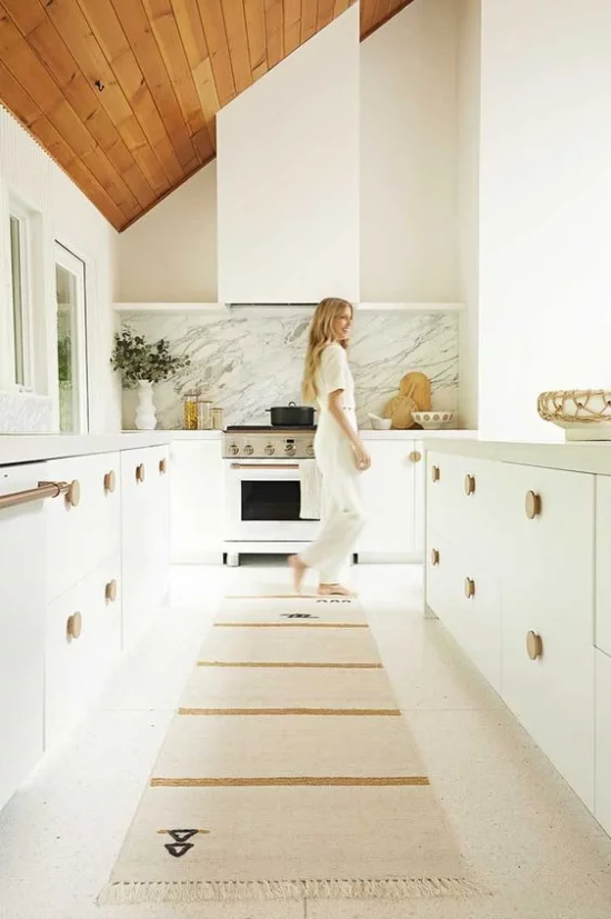 integrierte Dunstabzugshaube Eleganz im Küchendesign junge Frau weiße Küche Rückwand aus hellgrauem Marmor